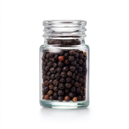 This image features a clear glass jar filled with whole black peppercorns, perfect for enhancing dishes and showcasing culinary details in food photography.の素材