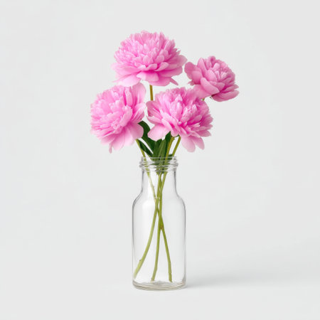 Beautiful arrangement of fresh pink flowers in a glass bottle, set against a light background. Ideal for home decor inspiration and floral design.の素材