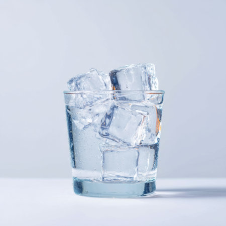 A clear glass filled with ice cubes and water, set against a white background, perfect for refreshing drink visuals and summer beverage themes.の素材