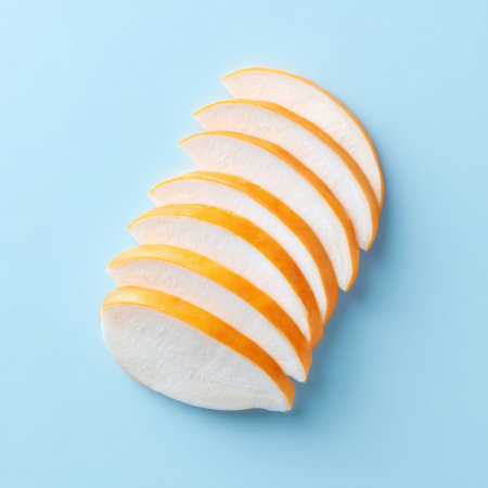 This image features perfectly arranged slices of a fresh fruit with bright orange and white colors against a light blue background, ideal for healthy eating themes.の素材