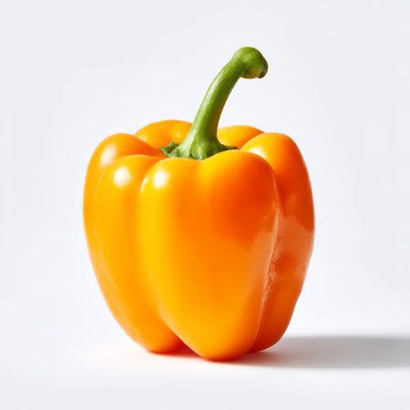 A fresh and vibrant yellow bell pepper stands alone against a clean white background, highlighting its smooth texture and appealing color, perfect for culinary visuals.の素材