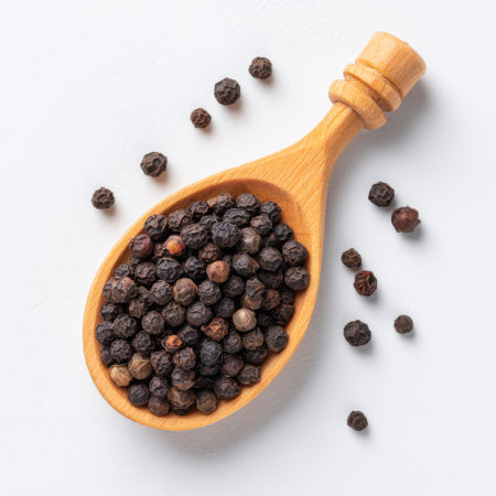 A wooden spoon filled with black peppercorns showcases the rich texture and color of this essential cooking ingredient, perfect for food lovers.の素材