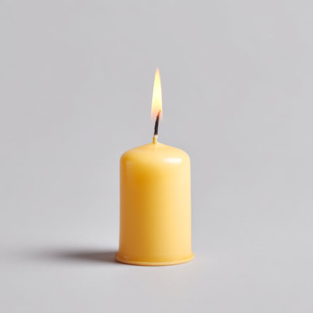A vibrant yellow candle burns steadily against a grey background, creating a calming ambiance. Ideal for relaxation, meditation, or home decoration purposes.の素材