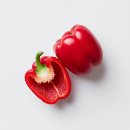 This vibrant red bell pepper, neatly halved, offers a stunning visual appeal on a clean white backdrop, perfect for culinary inspirations and healthy recipes.の素材