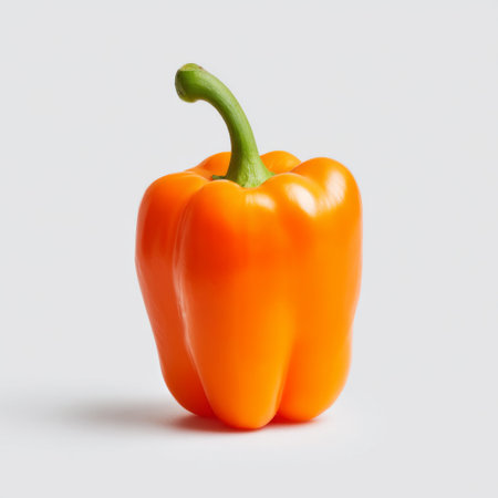A vibrant orange bell pepper isolated on a clean white background, perfect for showcasing healthy eating, cooking inspiration, and vegetable freshness.の素材