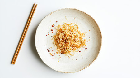 A used plate with leftover fried noodles and chopsticks beside it, isolated against a white background, signifying a completed meal.の素材
