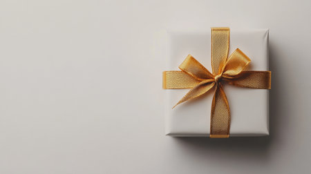 A pristine white gift box wrapped in real gold ribbon, isolated on a clean white background, perfect for showcasing sophistication and luxury.の素材