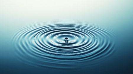 Raindrops making circular ripples on the surface of blue water, evoking a sense of serenity and the peaceful beauty of a rainy day.の素材