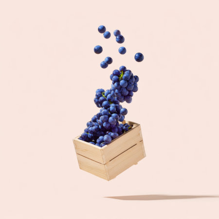 A captivating image of fresh purple grapes floating above a wooden crate, showcasing their vibrant color against a light beige background, perfect for food-related themes.の素材