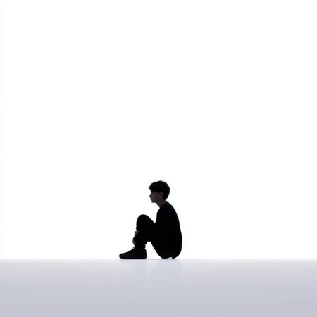 A solitary young person sits quietly against a minimalist background, evoking themes of introspection and emotional depth. Ideal for conveying tranquility.の素材