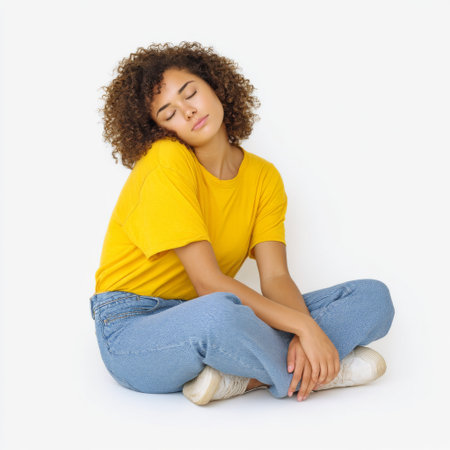 A young woman exudes tranquility while sitting cross-legged in casual attire, embodying a moment of peace and self-reflection against a simple backdrop.の素材