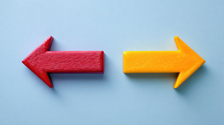 This image features two colorful wooden arrows, one red and one yellow, pointing in opposite directions. Perfect for concepts of choice and direction.の素材