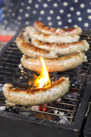 Tasty sausages cooking over the hot coals on a barbecue fireの写真素材