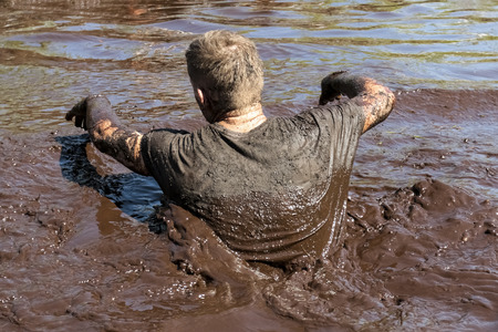 Muddy obstacle race runner in action. Mud run.の写真素材