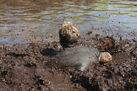 Muddy obstacle race runner in action. Mud run.