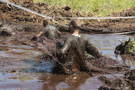 Muddy obstacle race runner in action. Mud run.の写真素材