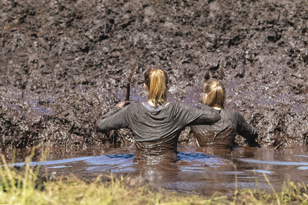 Muddy obstacle race runners in action. Mud run.の写真素材