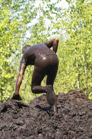 Muddy obstacle race runner in action. Mud run.の写真素材