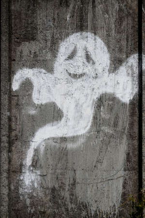 A street art graffiti painted on a concrete wall in the shape of a ghost.