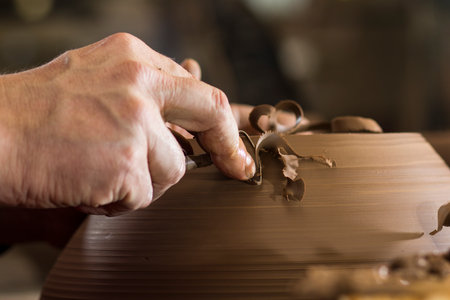 potter's hands working with clay on potter's wheel, forming bowl. Traditional pottery, craft...