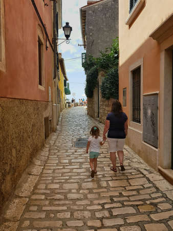 Woman and child walking hand in hand in a street of Rovinj, croatiaの素材