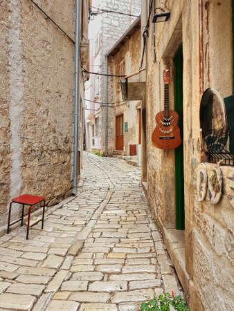 Guitar hanging on wall at ancient narrow street or Rovinj, Croatia Europeの素材