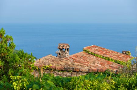 French Riviera: Scenic view of mediterranean coastline with medieval rooftop in foreground and space for textの写真素材