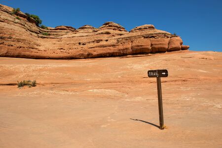 Trail sign in Arches National Park on rocky plateau with cliffs in background and copyspaceの写真素材