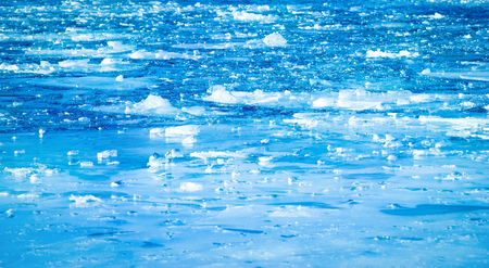 Blue frozen river with small floes in winter