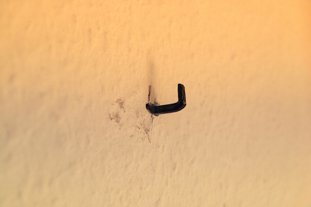 Iron wall hook on beige wall with much empty space
