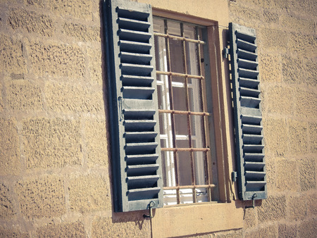 Old window with wooden shutters and metal grid