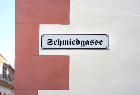 The German word for BLACKSMITH'S ALLEY hanging on a wall signの写真素材