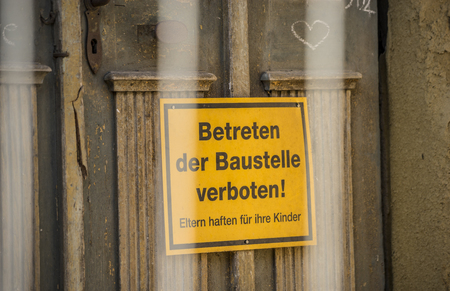 Yellow sign with the German words for BEWARE OF TRESPASSING THE CONSTRUCTION SITEの写真素材