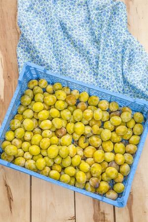 Fresh seasonal plum in box on the wooden backroundの写真素材