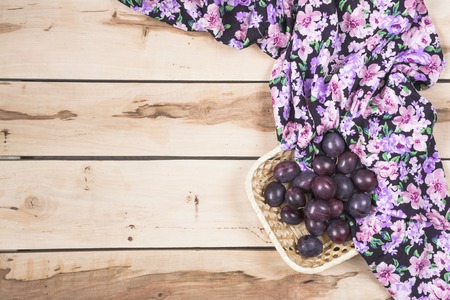 Fresh seasonal plums in a little basket with colorful napkinの写真素材