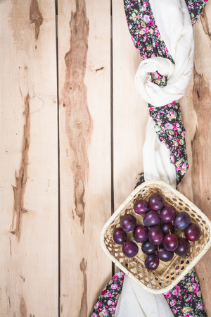 Fresh seasonal plums in a little basket with colorful napkinの写真素材