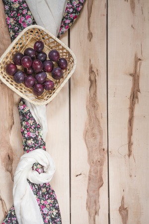 Fresh seasonal plums in a little basket with colorful napkinの写真素材