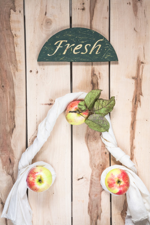 Fresh seasonal apples on the wooden background with napkinの写真素材