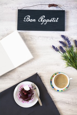 Cup of coffee with sweet dessert, beautiful flower and book on the tableの写真素材