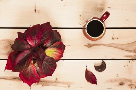 Cup of coffee with autumn leaves on the wooden backgroundの写真素材