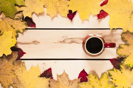 Cup of coffee with autumn leaves on the wooden backgroundの写真素材