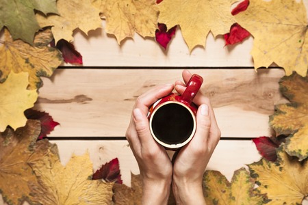Cup of coffee with autumn leaves on the wooden backgroundの写真素材