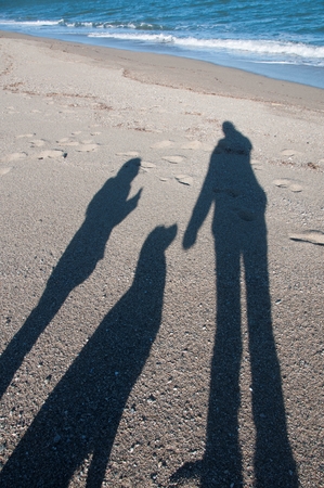 The shadow of a dog and its owner on a beachの写真素材