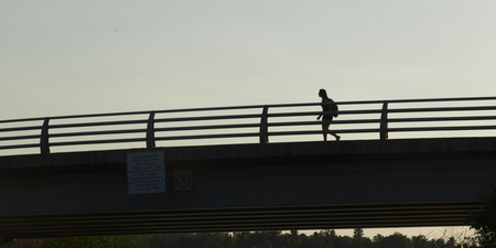 Low angle view of a woman walking on bridge, Kenora, Lake of the Woods, Ontario, Canadaの写真素材