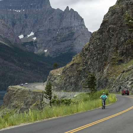 Person riding bicycle on mountain road, Going-to-the-Sun Road, Glacier National Park, Glacier County, Montana, USAのeditorial素材