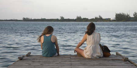Woman with her daughter sitting on a pier, Utila Island, Bay Islands, Hondurasの写真素材