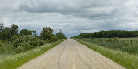 Gravel road passing through prairie landscape, Manitoba, Canadaの写真素材