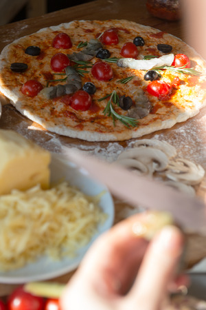 Woman cooking pizza at home. Unrecognizable woman cutting shrimp