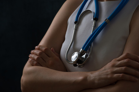 Futuristic modern unrecognizable female doctor with stethoscope standing with hands foldedの写真素材