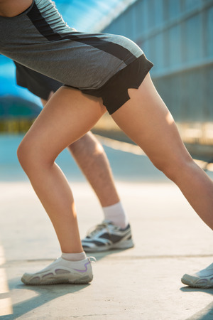 Unrecognizable couple stretching while standing in the city urban backgroundの写真素材